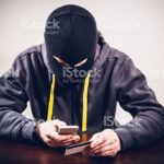Masked criminal stealing mobile phone payment information and passwords